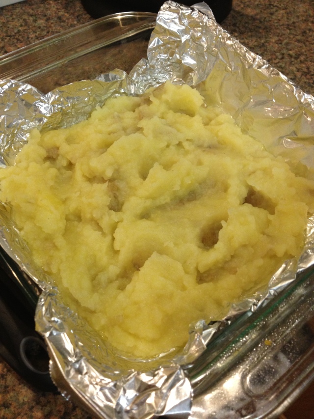 Next, I mixed the potatoes into mashed potatoes with lots of good seasonings and spread half of it into the baking dish.